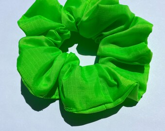 May include: A bright green scrunchie made of a textured fabric.