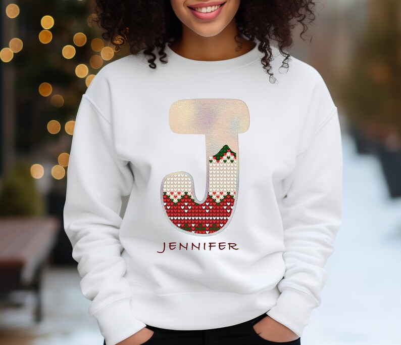 May include: White sweatshirt with a red, green, and white knit letter J. The letter is outlined in silver glitter. The name Jennifer is printed below the letter.