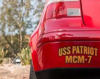 May include: A red car with a gold sticker that says "USS PATRIOT MCM-7" on the back bumper.