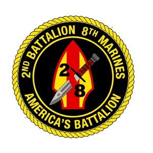 May include: A circular emblem with a black border and a gold rope-like edge. The text "2ND BATTALION 8TH MARINES AMERICA'S BATTALION" is in gold. A red and yellow arrow shape contains the numbers "2" and "8" with a knife and sheath.
