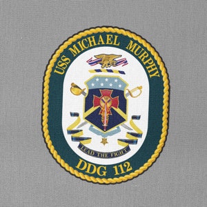 May include: A navy blue patch with a gold rope border and the text "USS MICHAEL MURPHY DDG 112" around the edge. The centre of the patch features a white shield with a red cross and a gold sword. The text "LEAD THE FIGHT" is below the shield.