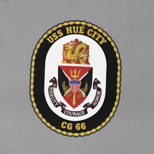 Könnte beinhalten: Ein schwarzer und weißer runder Patch mit einem goldenen Kettenrand. Der Patch zeigt ein Wappen mit einem roten Schild, einer goldenen Krone und dem Text "USS HUE CITY CG 66".