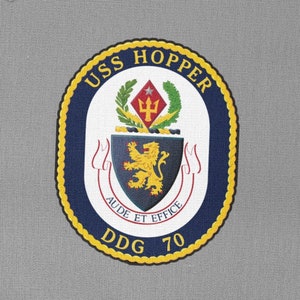 May include: A navy blue patch with a gold border and the text "USS HOPPER DDG 70". The patch features a crest with a lion, a trident, and the text "AUDE ET EFFICE".