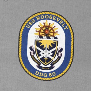 May include: A blue and gold embroidered patch with the text "USS ROOSEVELT DDG 80" and a crest featuring a sun, sword, and crossed swords. The crest is surrounded by a rope border.