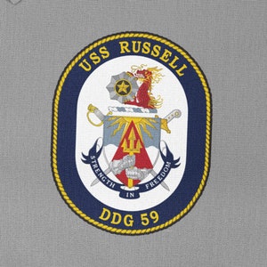 Könnte beinhalten: Ein gestickter Aufnäher in Marineblau und Gold mit dem Text "USS RUSSELL DDG 59" und einem Wappen mit einem roten Drachen, Schwertern und einem Dreizack.