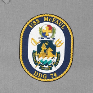 May include: A navy blue and gold embroidered patch with the words "USS McFAUL DDG 74" and a crest featuring a trident, a horse, and the words "Courage, Honour, Sacrifice".
