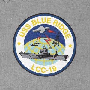 Pode incluir: Um remendo circular com fundo azul e letras brancas. O remendo diz "USS BLUE RIDGE LCC-19". O remendo apresenta um navio com um satélite e raios no fundo.