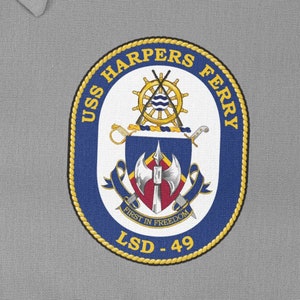 Op de afbeelding: Een blauwe en gouden ronde patch met de tekst "USS HARPERS FERRY LSD-49" en een wapenschild met een gekruist zwaard en bijl, een scheepswiel en een lint met de tekst "FIRST IN FREEDOM".