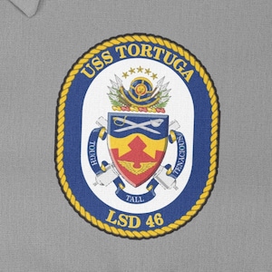 May include: A navy blue patch with a gold rope border and the text "USS TORTUGA LSD 46". The patch features a crest with a red, yellow, and blue shield, crossed swords, and the words "Tough, Tall, Tenacious".