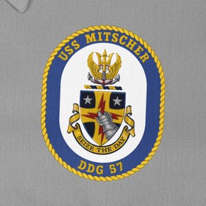 May include: A yellow and blue circular patch with the text "USS Mitscher DDG 57" and the words "Seize the Day" on a white shield with a lightning bolt and a star.