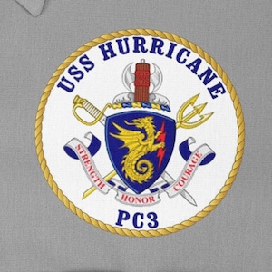 Pode incluir: Um remendo circular branco e dourado com uma borda de corda. O remendo apresenta um brasão com um dragão, espadas e um tridente. O texto "USS HURRICANE PC3" está impresso no remendo.