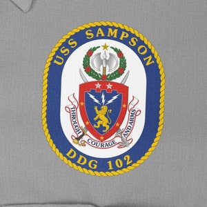 May include: A blue and gold circular patch with the text "USS SAMPSON DDG 102" and a crest featuring a lion, lightning bolts, and the words "Through Courage and Arms".