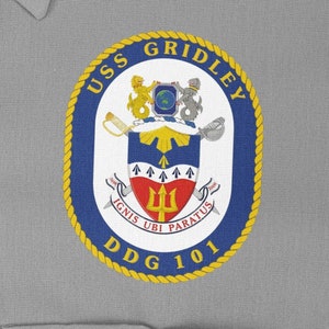Può includere: Una toppa ricamata blu navy e oro con il testo "USS GRIDLEY DDG 101" e uno stemma con un tridente e la frase latina "IGNIS UBI PARATUS".