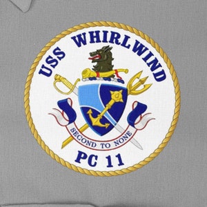 Pode incluir: Um remendo circular branco e dourado com o texto "USS WHIRLWIND PC 11" e um brasão com um lobo, uma espada, uma âncora e um tridente.