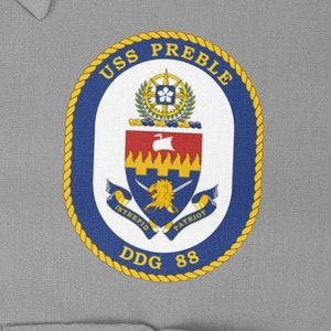 Könnte beinhalten: Ein blauer und goldener runder Aufnäher mit dem Text "USS PREBLE DDG 88" und einem Wappen mit einem Löwen, einem Schwert und den Worten "INTREPID PATRIOT".