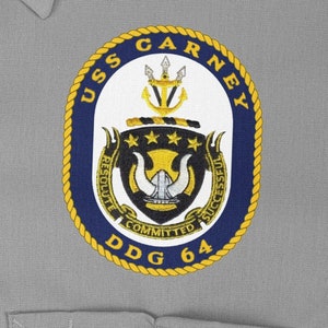 May include: A navy blue and gold embroidered patch with the text "USS CARNEY DDG 64" and a crest featuring a ship's wheel, three stars, and a trident.