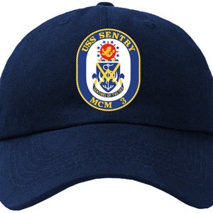 Könnte beinhalten: Eine marineblaue Baseballkappe mit einem goldenen gestickten Aufnäher mit den Worten "USS SENTRY MCM 3" und einem Wappen mit einem Anker und den Worten "Sentinel of the Sea".