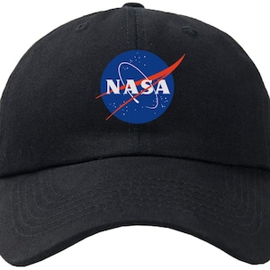 May include: A black baseball cap with the NASA logo in blue, red, and white. The logo features a red curved line and a blue circle with white stars and the word "NASA" in white.