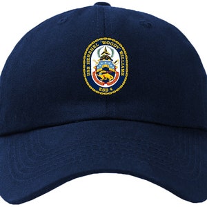 Puede incluir: Una gorra de béisbol azul marino con un escudo bordado en oro con el texto "USS HERSCHEL "WOODY" WILLIAMS  ESB 4".