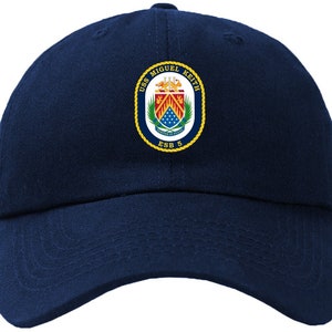 Puede incluir: Una gorra de béisbol azul marino con un parche bordado en oro que presenta el escudo de armas del USS Miguel Keith y el texto "USS Miguel Keith ESB 5".