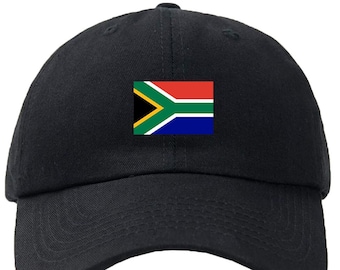 May include: Black baseball cap featuring the South African flag on the front. The flag is rectangular and includes a yellow, green, white, red, blue, and black design. The cap has a curved brim and an adjustable strap.