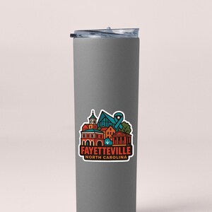 A gray insulated tumbler with a colorful sticker depicting the town of Fayetteville, North Carolina.