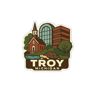 May include: A sticker featuring a stylized illustration of Troy, Michigan. The design includes a church, a modern building, trees, a pond, and a turtle. The text "TROY MICHIGAN" is at the bottom in a brown banner.