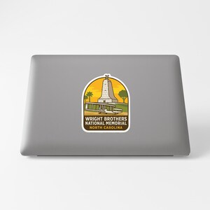 A sticker on the back of a laptop, depicting a tall structure with a palm tree in the background.