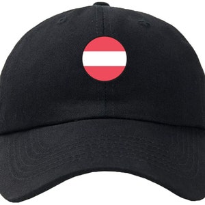 May include: A black baseball cap with a red and white circle featuring the flag of Austria.
