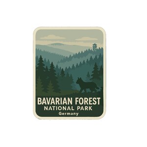 Puede incluir: Una pegatina rectangular con una ilustración paisajística del Parque Nacional de la Selva Bávara en Alemania. El diseño incluye una silueta de lobo, pinos y el texto "Bavarian Forest National Park Germany."
