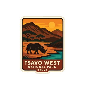 Op de afbeelding: Een rechthoekige sticker met een neushoorn in een landschap met bergen, bomen en een rivier. De sticker heeft de tekst "TSAVO WEST NATIONAL PARK KENYA" in bruine letters op een witte achtergrond.