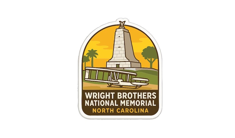 a sticker or emblem with a tall tower and a biplane, representing the Wright Brothers National Memorial in North Carolina.