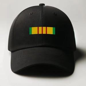 May include: Black baseball cap with a green, yellow, and red embroidered ribbon on the front. The ribbon has four yellow stripes.