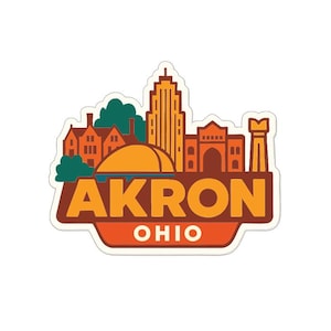 Puede incluir: Una pegatina con el horizonte de Akron, Ohio, en naranja, marrón y verde. La palabra "AKRON" se muestra de forma destacada, con "OHIO" debajo. El diseño incluye edificios, árboles y un sol estilizado.