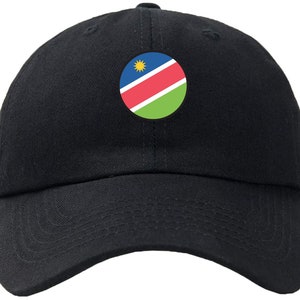 Op de afbeelding: Een zwarte baseballpet met een ronde patch met de vlag van Namibië. De vlag is blauw, rood en groen met een gele zon in de linkerbovenhoek.
