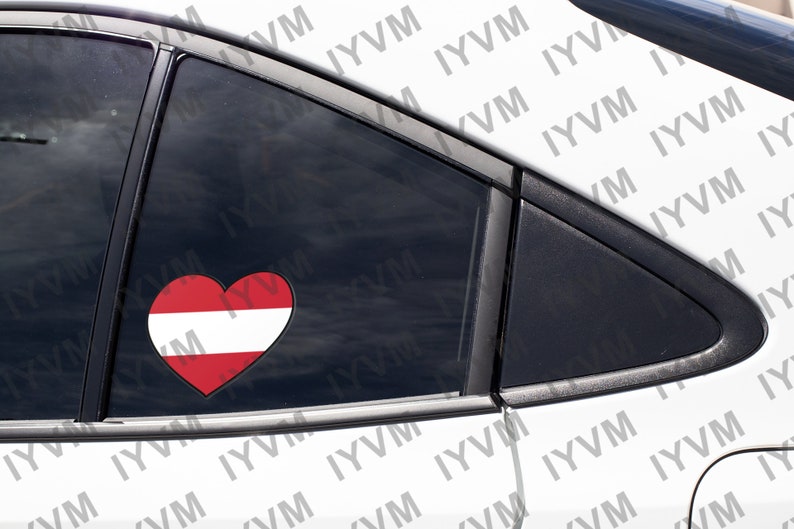 May include: A white car with a heart-shaped sticker on the back window. The sticker is red and white and features the Austrian flag.