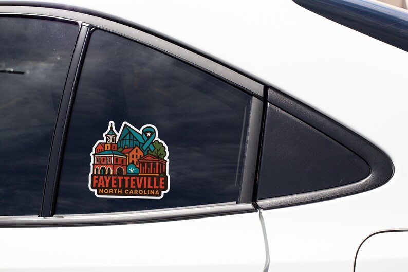 A sticker on the side of a car window, featuring a colorful illustration of a building and the text "FAYETTEVILLE NORTH CAROLINA".
