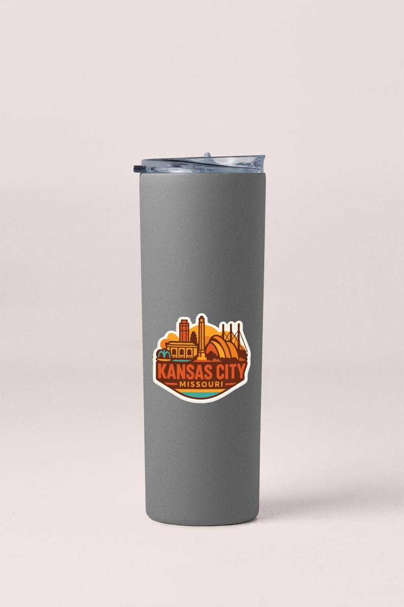 A gray insulated tumbler with a sticker depicting the Kansas City skyline.