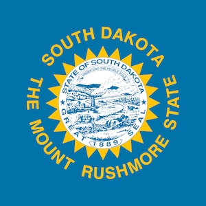 Könnte beinhalten: Die offizielle Flagge von South Dakota, mit einem blauen Hintergrund und einem gelben Sonnenstrahl, der das Staatssiegel umgibt. Das Siegel zeigt eine Landschaft mit einem Fluss, Bergen und den Worten "State of South Dakota" und "Great Seal" in einem Kreis um das Bild. Der Text "The Mount Rushmore State" ist in einem Kreis um den Sonnenstrahl geschrieben.