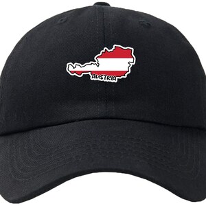 May include: Black baseball cap with a white-bordered outline of Austria, filled with the Austrian flag's red and white stripes. The word "AUSTRIA" is printed in white. The cap has a curved peak and an adjustable strap.