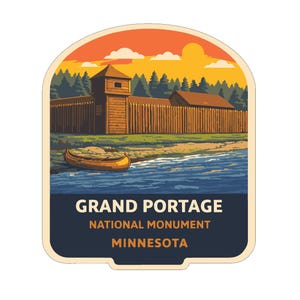 May include: A sticker featuring a landscape of Grand Portage National Monument in Minnesota. The image shows a wooden fort, a canoe on the water, and a sunset. The text "GRAND PORTAGE NATIONAL MONUMENT MINNESOTA" is at the bottom.