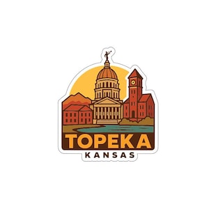 May include: A sticker featuring a stylized illustration of Topeka, Kansas. The design includes the state capitol building, a clock tower, and the text "TOPEKA KANSAS" in a brown and white color scheme, set against a yellow and orange background.