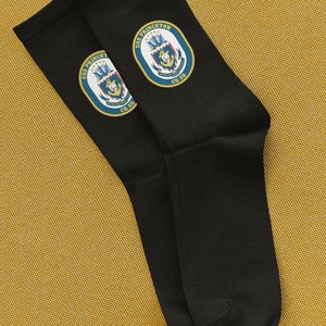 Könnte beinhalten: Ein Paar schwarze Socken mit einem gestickten Aufnäher in Marineblau und Gold mit dem Text "USS PRINCETON CG 59".