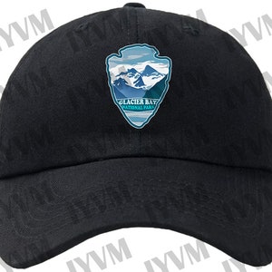 May include: Black baseball cap with a Glacier Bay National Park logo featuring a mountain range and a blue and white arrowhead design.