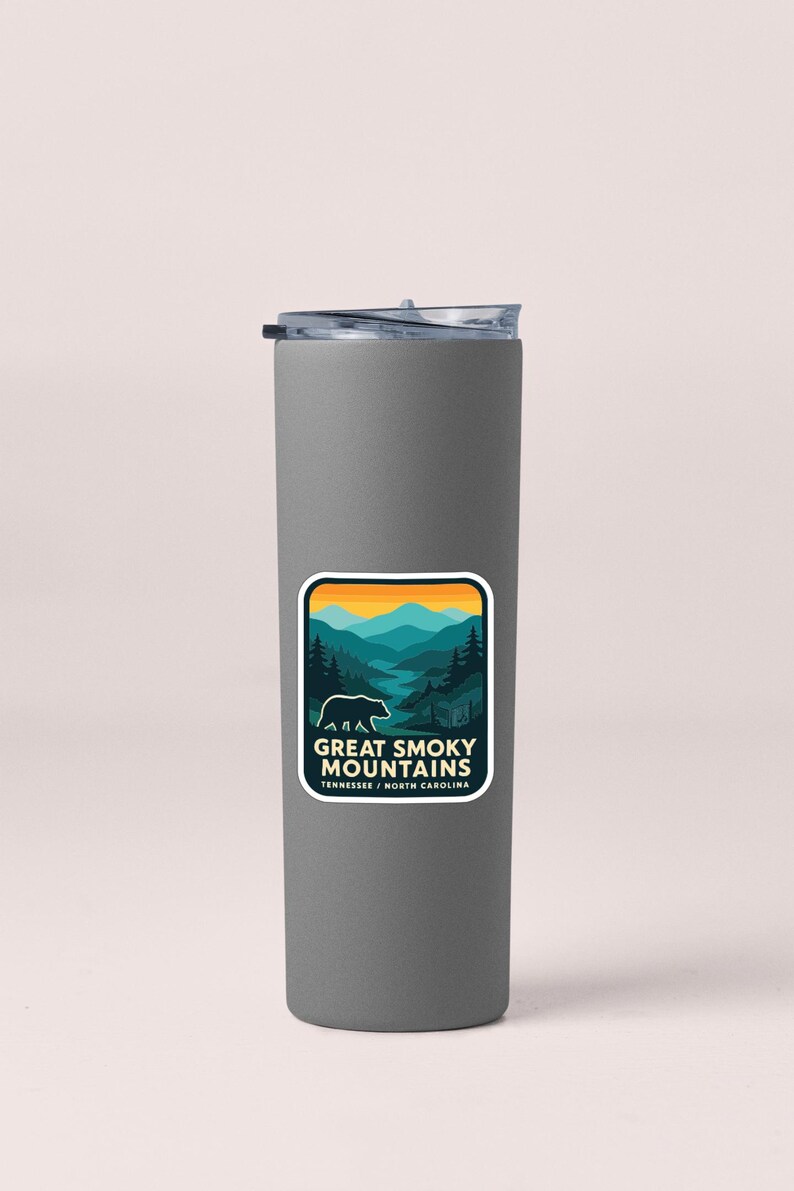 A gray insulated tumbler with a sticker featuring a mountain landscape and the text "Great Smoky Mountains National Park, Tennessee, North Carolina".