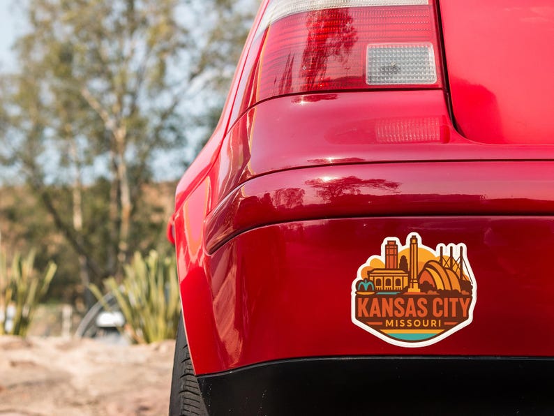 the rear end of a red car with a sticker on the back that says "KANSAS CITY MISSOURI".
