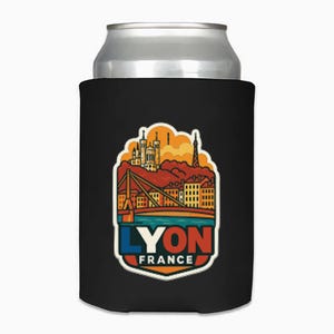 May include: Black can cooler with a colorful graphic of Lyon, France. The design includes a bridge, buildings, and the text "LYON FRANCE" in blue, orange, and white. The cooler is designed to keep beverages cold.