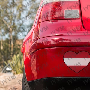 May include: A red car with a heart-shaped sticker of the Austrian flag on the back bumper.