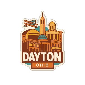 May include: A sticker featuring a stylized illustration of Dayton, Ohio landmarks. The design includes a biplane, buildings, and the text "DAYTON OHIO" in a vintage style, with a color palette of brown, orange, and teal.