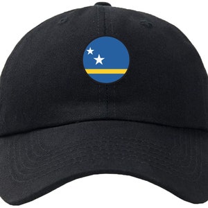 May include: A black baseball cap with a circular patch featuring the flag of Curaçao. The flag is blue with two white stars and a yellow stripe.